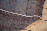 Distressed Belouch carpet corner and short fringe, with faded copper orange and blue hues.