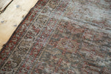 Distressed Malayer runner's intricate border, showcasing muted charcoal brown and moss green tones.