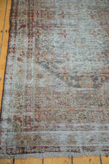 Distressed Malayer runner corner with faded intricate borders, charcoal, and ivory fringe.