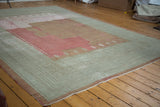 Distressed Ghiordes carpet with geometric sea foam green border and faded raspberry field.