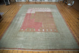 Distressed Ghiordes carpet texture, highlighting raspberry red field and sea foam green geometric border.