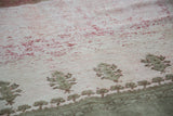 Distressed Ghiordes carpet texture, blush field with raspberry red wear, sea foam geometric motifs.