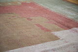 Distressed Ghiordes carpet texture with soft raspberry red, blush, and muted beige tones.