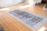 Distressed hand-knotted Khotan runner detail, featuring navy blue, saffron gold, and ivory floral design.