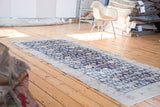 Distressed navy blue Khotan runner displaying geometric pomegranate and floral patterns in gold and ivory.