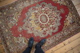 Distressed Turkish Oushak rug with faded cinnabar red and worn gold medallion design.