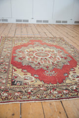 Distressed Turkish Oushak rug, intricate cinnabar red and gold medallion details.
