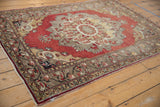 Distressed Oushak rug with fringed edge, intricate border, cinnabar red, gold, charcoal patterns.