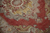 Distressed vintage Oushak rug showing faded cinnabar red and gold traditional motifs.