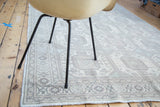 Distressed Kaisary rug corner, geometric octagonal guls in ivory, soft green, blush.