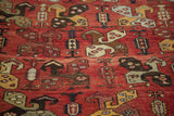 Repeating tribal pattern featuring stylized boteh motifs in madder red, saffron, and plum tones.