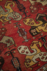 Rectilinear tribal motifs in yellow, grey, and brown on a madder red Oushak runner.
