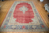 Distressed Oushak carpet with star medallion, cherry red field, blue and beige borders.
