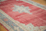 Decorative distressed cherry red Oushak rug showing star medallion and grey-beige border.
