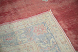 Distressed cherry red Oushak rug texture and patterned border, showing weave on reverse.