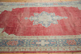 Distressed cherry red Oushak carpet field with grey and beige star medallion and border.
