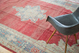 Vintage distressed Oushak carpet: faded red pile with grey and beige border pattern.