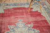 Decorative distressed cherry red Oushak rug showing worn pile texture and beige, grey patterns.