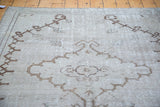 Distressed vintage Oushak carpet texture with contrasting brown stylized geometric patterns.