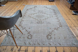 Distressed vintage Oushak rug, striking brown diamond medallion on a neutral faded ground.