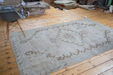 Distressed Turkish Oushak carpet corner with faded texture and brown angular motifs.