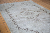 Distressed Oushak carpet close-up, light beige ground, strong brown geometric outlines.