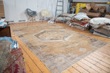 Faded central geometric medallion on a distressed Oushak carpet.