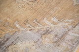Textured geometric tribal pattern of a distressed Oushak carpet in earth tones.