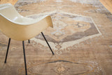 Distressed hand-knotted Oushak rug showing worn geometric design in earth tones.