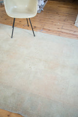 Distressed vintage Turkish Oushak carpet with faded apricot field and subtle green tones.