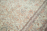 Distressed Turkish carpet's faded grey-green field, allover coral floral, and patterned border.