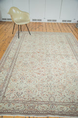 Distressed Kaisary rug corner, showing muted floral motifs, faded grey-green field, and fringe.