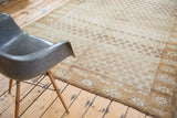 Repeating gold and ivory floral panel design on a distressed Oushak carpet with abrashes.