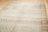 Ivory distressed Oushak rug with bronze geometric bands and faint floral patterns.