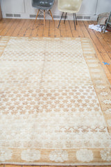 Distressed Oushak carpet with repeating gold and bronze abrashes and shadow floral patterns.