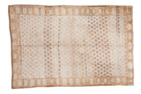 Distressed Oushak carpet featuring repeating panel and shadow floral designs in ivory, gold, brown.