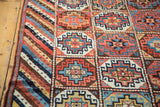 Vibrant geometric gul panel motifs with varied colors alongside the striped tribal border.