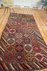 Hand-knotted tribal geometric gul motifs in madder red, indigo, and saffron on the runner.