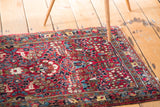 Vintage Sarouk mat featuring intricate floral bouquets in navy, aqua, and saffron on a cherry red field.