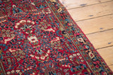 Vintage Sarouk rug detail, featuring cherry red field, colorful floral bouquets, and patterned border.