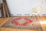 Corner detail of distressed vintage Oushak rug, showing cinnabar red field and expressive geometric spandrels in ivory.