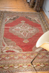 Distressed cinnabar red field, serrated ivory medallion, and expressive corner spandrel of an Oushak.