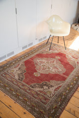 Angled detail of a traditional distressed Oushak rug, cinnabar red field and serrated ivory spandrels.