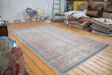 Distressed vintage Kaisary carpet, showing faded floral pattern and blue geometric border.