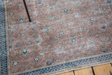 Distressed Turkish Kaisary carpet with storied texture, burnt raspberry floral motifs, navy border.