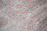 Distressed pile texture of a Kaisary carpet, revealing faded raspberry and blue floral motifs.