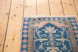 Fringed corner of a hand-knotted Oushak rug, dusty rose spandrel, teal field, ivory motif.