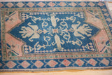 Detail of vintage Oushak rug: dusty rose spandrel and teal blue border with fruit motif.