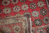 Vintage Oushak rug corner displaying red floral motifs and intricate hand-knotted reverse.