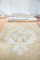 Distressed Oushak carpet featuring a dramatic medallion with primitive vine motifs and soft wooded tones.